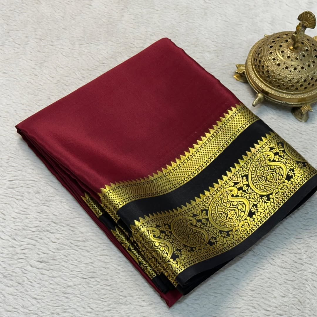 Maroon saree with gold and black border on a textured white surface