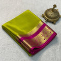 Green and pink saree with gold border on a light gray background
